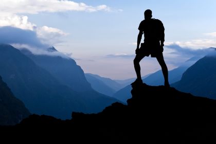 man-hiking-success-silhouette-in-mountains-2021-08-26-22-35-24-utc-scaled.jpg
