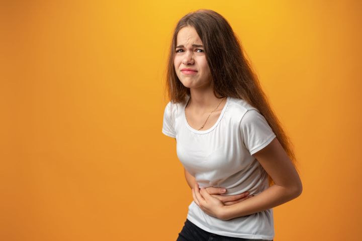 teenage-girl-with-stomach-ache-against-yellow-back-2022-02-24-07-54-22-utc-scaled.jpg